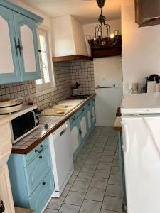 eine Küche mit blauen Schränken und weißen Geräten in der Unterkunft Gîte campagnart 