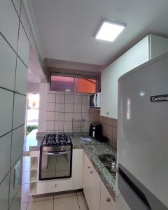 a kitchen with a stove and a refrigerator at diRoma Fiori 89 com roupa de cama e banho. in Caldas Novas