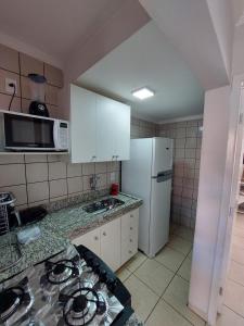 a kitchen with white cabinets and a white refrigerator at diRoma Fiori 89 com roupa de cama e banho. in Caldas Novas