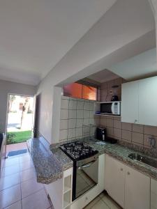 a kitchen with a stove top oven next to a counter at diRoma Fiori 89 com roupa de cama e banho. in Caldas Novas