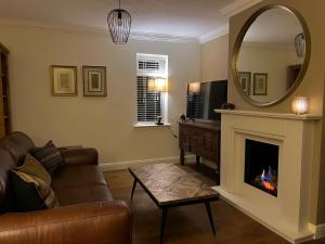 a living room with a couch and a mirror at Stunning Beverley Bungalow w Fireplace, private parking, and garden in Beverley