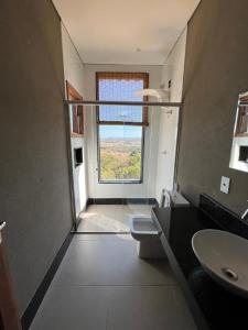 uma casa de banho com um lavatório, um WC e uma janela. em Casa da Vista - LAGOA SANTA em Lagoa Santa