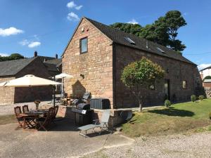 a brick building with a table and chairs and umbrella at 2 Bed Classy Peak District Cottage Barn Near Alton Towers, Polar Bears, Chatsworth House in Whiston