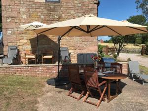 a table and chairs under an umbrella in a yard at 2 Bed Classy Peak District Cottage Barn Near Alton Towers, Polar Bears, Chatsworth House in Whiston