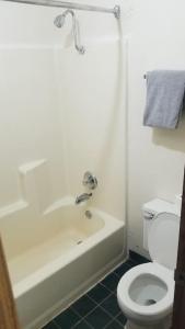 La salle de bains est pourvue d'une baignoire blanche et de toilettes. dans l'établissement OSU 2 Queen Beds Hotel Room 232 Wi-Fi Hot Tub Booking, à Stillwater