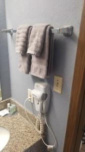 a bathroom with towels and a hair dryer on a wall at OSU 2 Queen Beds Hotel Room 232 Wi-Fi Hot Tub Booking in Stillwater