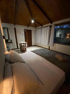 a large white bed in a room with a table at Chalé Lírio do Campo in Ouro Preto
