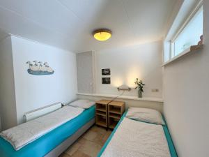 a bedroom with two beds and a desk and a window at Gelijkvloers Vakantieappartement 150m van Strand Egmond aan Zee in Egmond aan Zee
