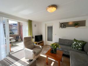 a living room with a couch and a chair at Gelijkvloers Vakantieappartement 150m van Strand Egmond aan Zee in Egmond aan Zee