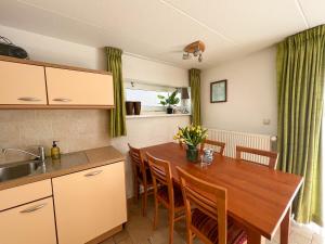 a kitchen and dining room with a wooden table and chairs at Gelijkvloers Vakantieappartement 150m van Strand Egmond aan Zee in Egmond aan Zee