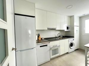 Il comprend une cuisine blanche équipée d'un réfrigérateur et d'un lave-vaisselle. dans l'établissement Apartamento Aguacate beach playa Granada, à Motril