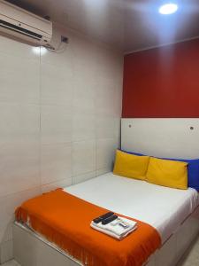 リオアチャにあるHotel la Sierra Riohacha Iの小さなベッドルーム(黄色とオレンジのシーツが敷かれたベッド1台付)