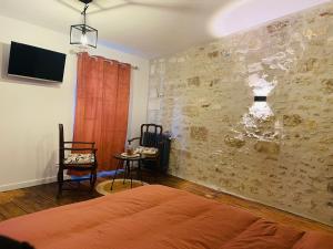 1 dormitorio con cama y pared de piedra en Les Dames Jeannes, en Jarnac