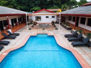 einen Pool mit Stühlen und ein Haus in der Unterkunft Hotel Costa Pacifica in Esterillos