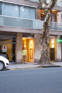 a person walking in front of a building with a tree at * Grand Oro * in Buenos Aires