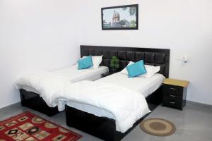 two beds with white and blue pillows in a room at Khajuraho Glory Homestay in Khajurāho +162 photos