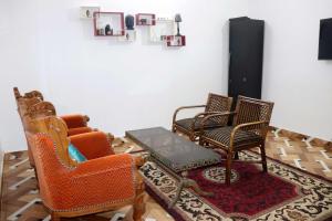 卡修拉荷的住宿－Khajuraho Glory Homestay，客厅配有三把椅子和一张桌子