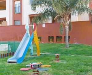 a playground with a slide in the grass with a palm tree at Apartment Isla Canela Luxury in Huelva