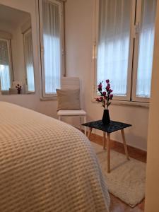Un dormitorio con una cama y una mesa con un jarrón de flores en Casa Roman SPORT, en León