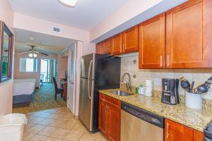 a kitchen with wooden cabinets and a stainless steel refrigerator at Towers On The Grove 724 Direct Oceanfront Suite Sleeps 6 guests in Myrtle Beach