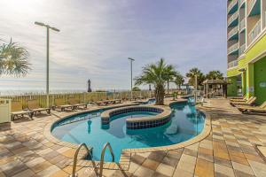 a swimming pool with benches and a building at Towers On The Grove 724 Direct Oceanfront Suite Sleeps 6 guests in Myrtle Beach