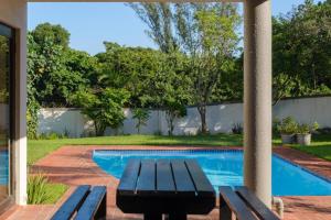 a patio with a picnic table next to a swimming pool at Escape to 85 Cascades in Umdloti Beach in Umdloti
