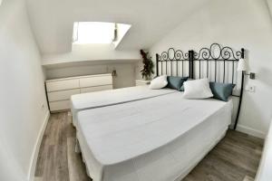 een witte slaapkamer met een groot wit bed met blauwe kussens bij Malaga Beach And Sun in Málaga