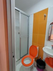 y baño con aseo de color naranja y ducha. en Hotel El Paisano en Villavicencio