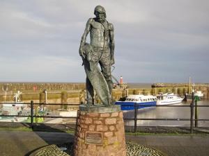 una estatua de un hombre sosteniendo un pez en Russets East Wing, en Isle Brewers