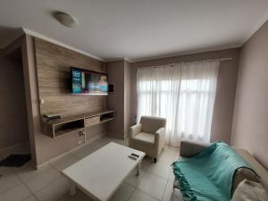 sala de estar con sofá, mesa y TV en Duplex Patagonia y Mar en Playa Unión