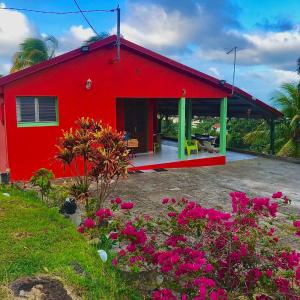 a red house with flowers in front of it at Maison de 2 chambres avec vue sur la mer spa et jardin clos a Le Robert a 6 km de la plage in Le Robert