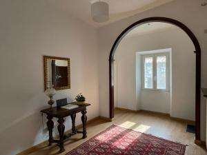 einen Torbogen in einem Zimmer mit einem Tisch und einem Fenster in der Unterkunft Nepi - Appartamento Centro Storico Duomo in Nepi