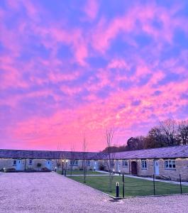una puesta de sol sobre un edificio con un cielo rosa en Briary Cottages at Iletts Farm, en Brackley