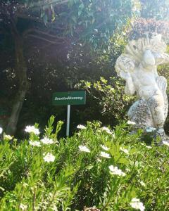 a sign in the middle of a garden with flowers at il Motto di Tommy in Castelveccana