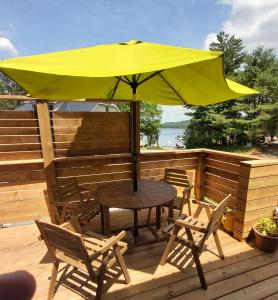 a table and chairs on a deck with a yellow umbrella at Oakview Lodge & Marina in Algonquin Highlands