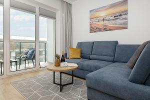 a living room with a blue couch and a table at Apartament AQUA BLUE Bridge Apartments & Spa Dziwnów EPapartamenty in Dziwnów