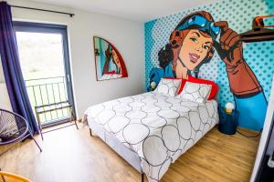 a bedroom with a bed with a painting of a woman at Paulette à bicyclette, vue sur la rivière, Esneux in Méry