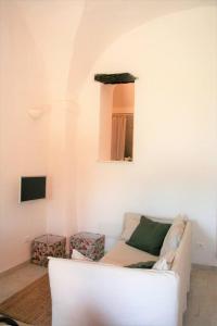een witte woonkamer met een bank en 2 krukken bij Casa Ninetta, tra mare e natura. in Finale Ligure