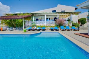 una piscina con sillas azules y una casa en The Natural Curacao, en Willibrordus