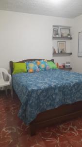 a bedroom with a bed with a blue blanket and green pillows at ELVIAJERO HOSTAL in Popayan