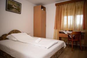 a bedroom with a bed and a desk and a window at AQUA Thermal Apartmanház II. in Püspökladány