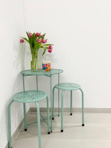 a table and two stools with a vase of flowers at Apartamentos Ruta da Auga in Ribadumia