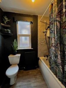 a bathroom with a toilet and a tub and a window at *Hot* Fantastic 3/4 Beds Town House in Anfield Stadium in Liverpool