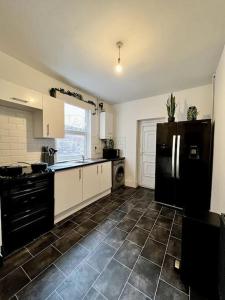 a kitchen with a black refrigerator and a tile floor at *Hot* Fantastic 3/4 Beds Town House in Anfield Stadium in Liverpool