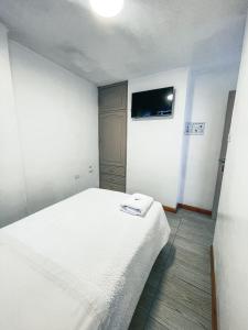 a bedroom with a white bed and a flat screen tv at Hotel Cisne in Cuenca