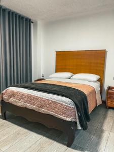 a bedroom with a large bed with a wooden headboard at Hotel Cisne in Cuenca