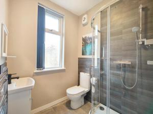 a bathroom with a toilet and a glass shower at Lindsay House - South Manchester Stylish Townhouse With Free Parking in Manchester