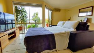 a bedroom with a bed and a flat screen tv at Grand Central Apartment in Toowoomba