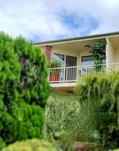 a house with a balcony and trees in the foreground at Grand Central Apartment in Toowoomba
