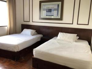 two beds in a hotel room with white sheets at Aisis Home at Afamosa in Kampong Alor Gajah